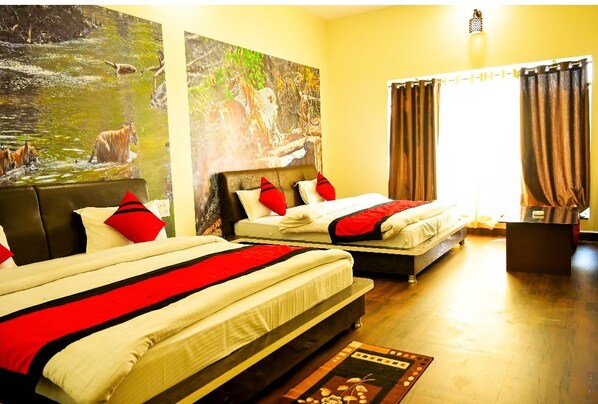 A hotel room with two beds, each with red and white bedding, a large painting of a river scene, and a window with curtains.