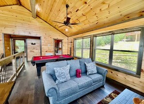A wooden interior with a pool table, a sofa, and large windows. - Bearly Behavin | Hot Tub Pool Table Great Location (Sevierville)