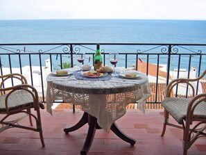 A round table with a lace tablecloth, two wicker chairs, and a bottle of olive oil. - Apartment in Nerja Near Carabeillo Beach (Nerja)