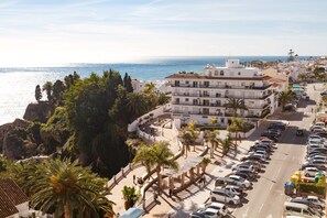 A coastal building with multiple balconies, a parking lot, and a view of the sea. - Apartment in Nerja Near Carabeillo Beach (Nerja)