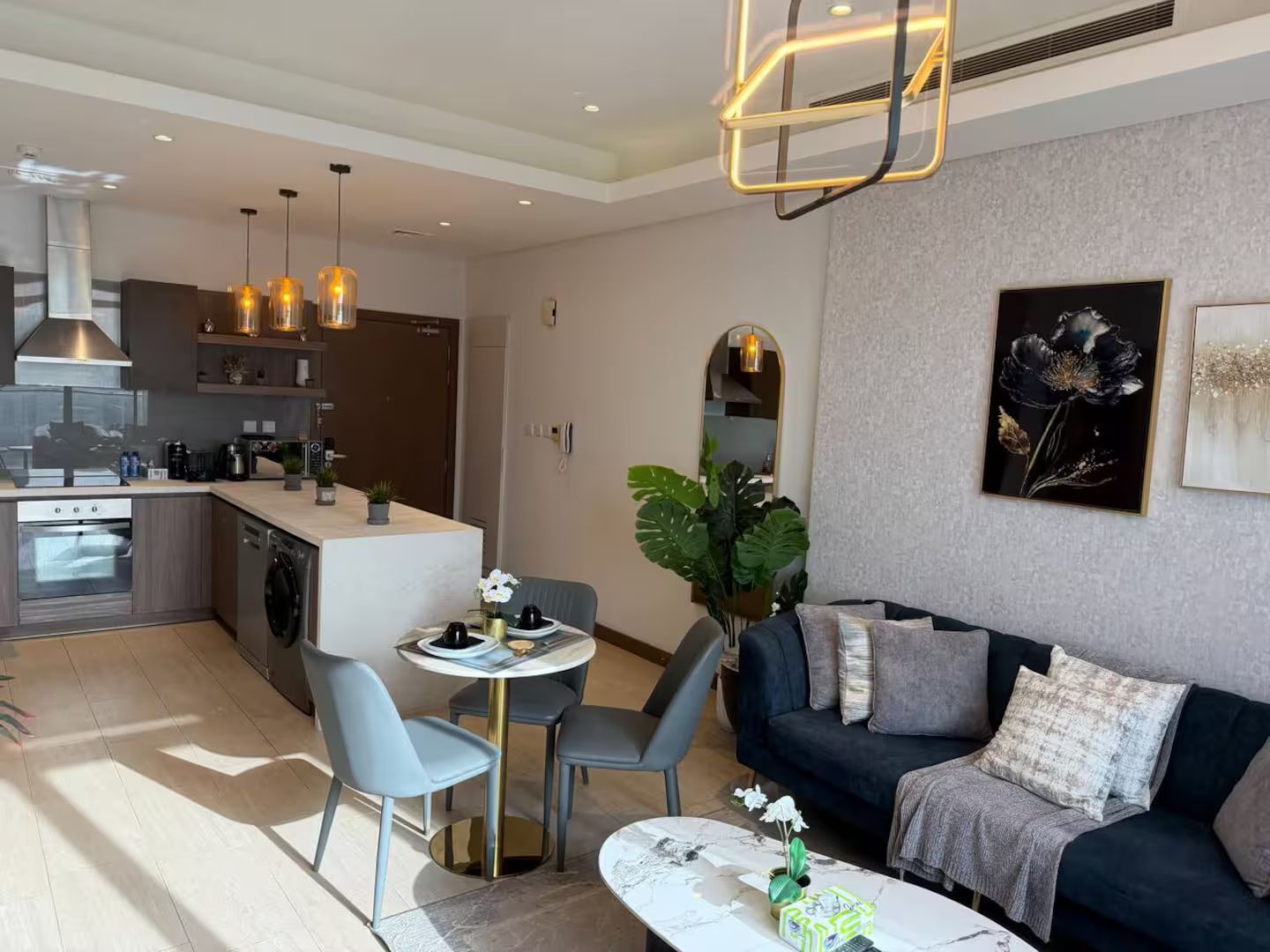 A modern living area with a sofa, a dining table, and a kitchen in the background.