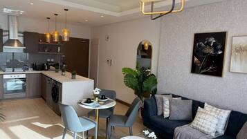 A modern living area with a sofa, a dining table, and a kitchen in the background.