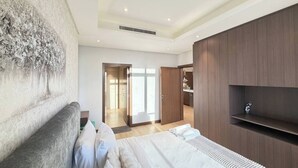 A modern bedroom with a large bed, a wooden wardrobe, and a door leading to a bathroom. - Stylish Downtown & Close to Attractions F97O (Manama)