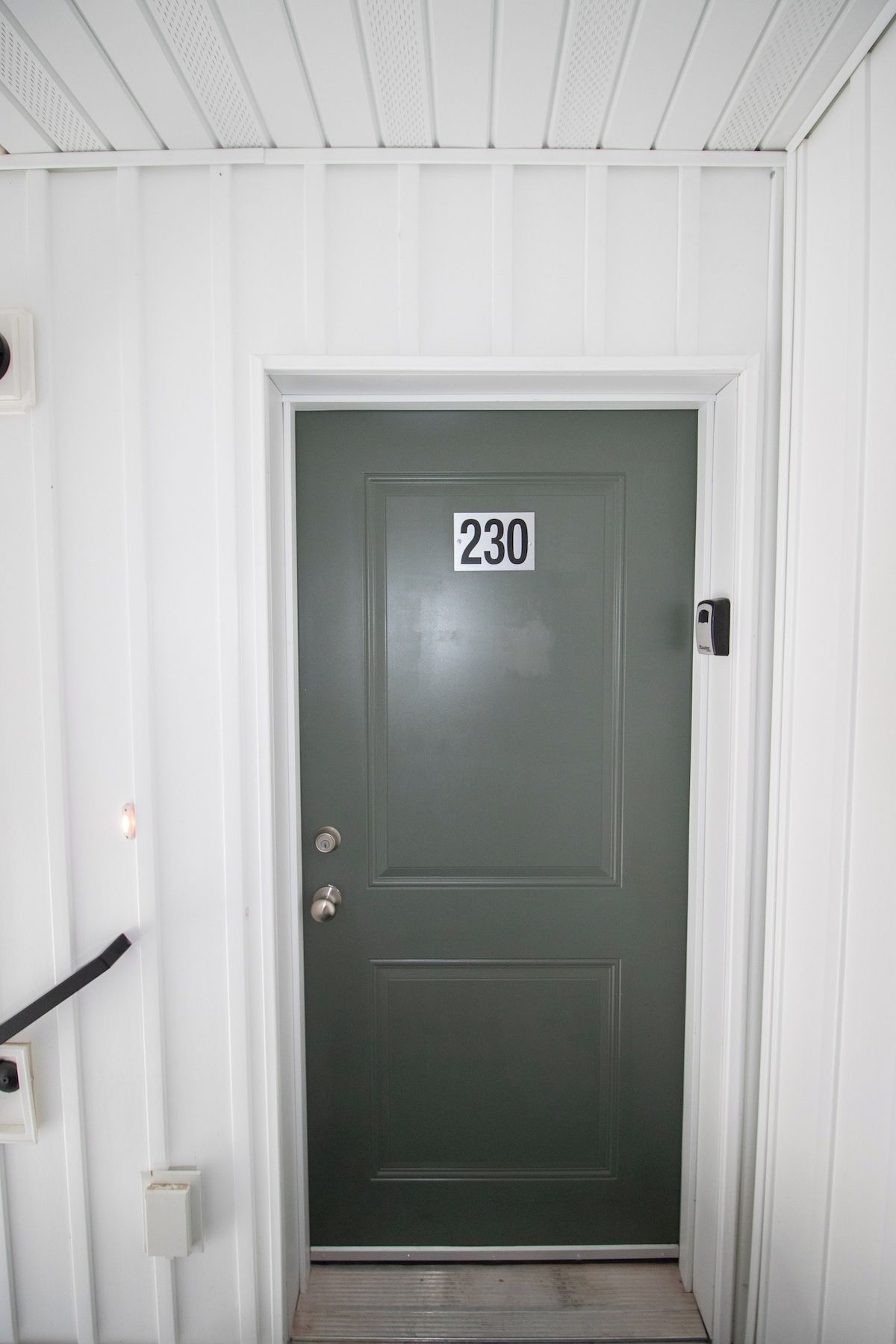 A door with the number 230, a doorbell, and a mail slot.
