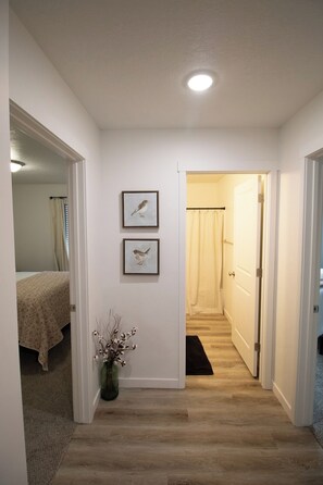 Ein Flur mit einem Bett, einer Tür und zwei gerahmten Bildern an der Wand.