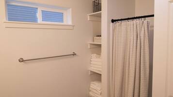 A bathroom with a shower curtain, a towel rack, and a window with blinds.