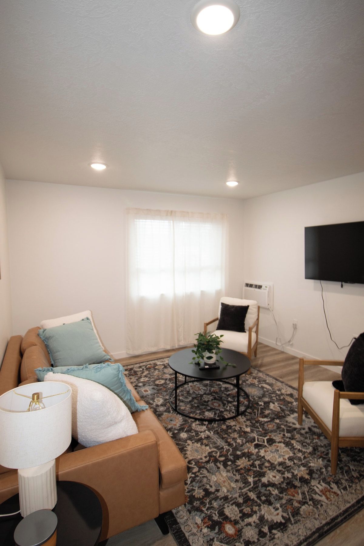 Un salon moderne comprenant un canapé, un fauteuil, une table basse et un téléviseur à écran plat fixé au mur.