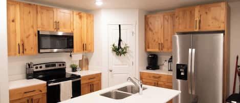 A modern kitchen with wooden cabinets, stainless steel appliances, and a central island with bar stools.