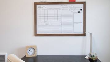 A desk with a whiteboard, a clock, and a chair.