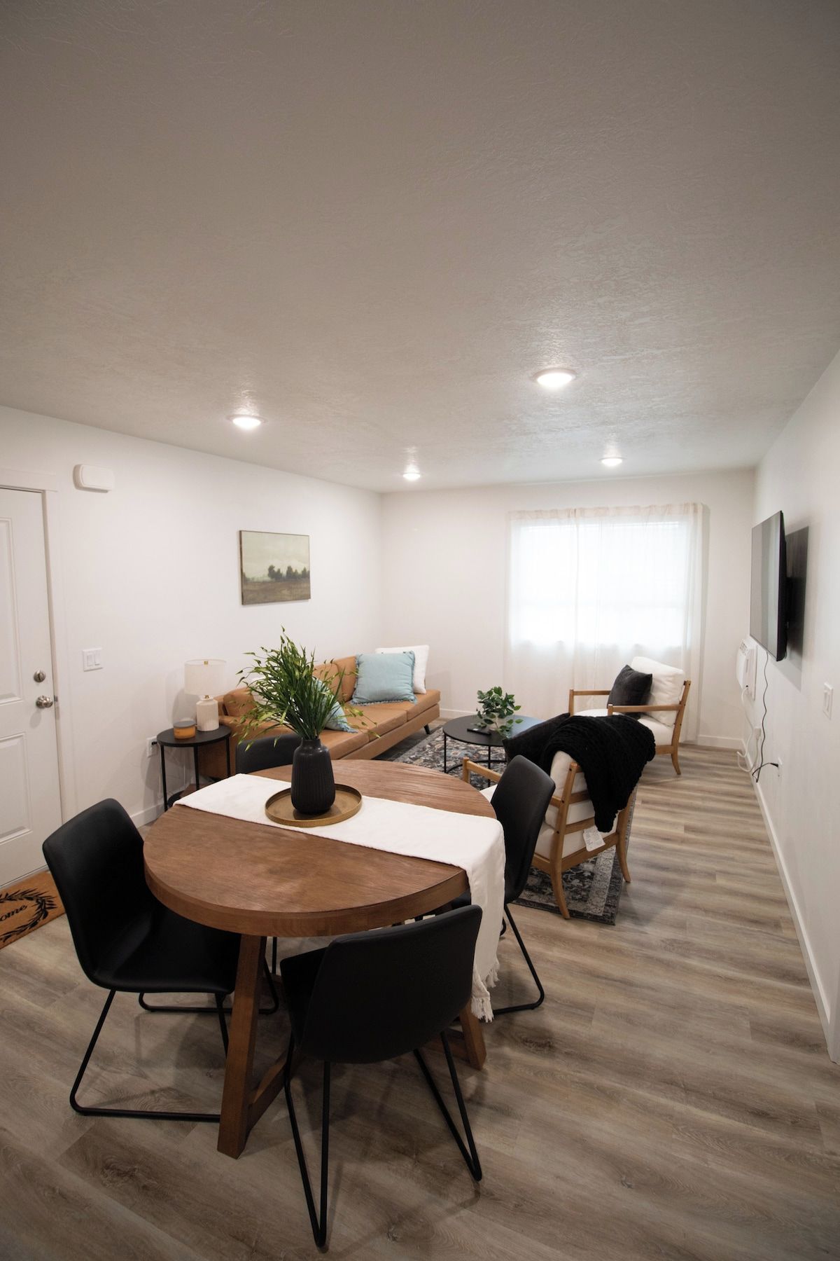 Un salon moderne comprenant une table à manger, des chaises, un canapé et un téléviseur.