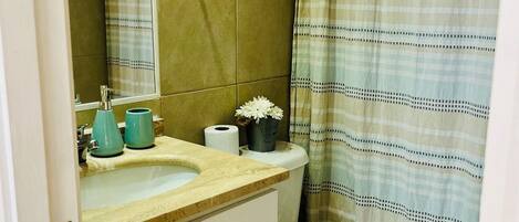Een badkamer met toilet, wastafel en spiegel.
