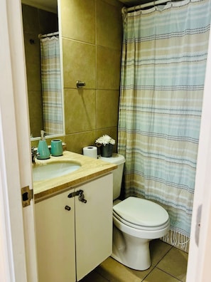 A bathroom with a toilet, sink, and mirror. - El mejor lugar - Hospital UC - Metro (Santiago)