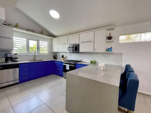 A modern kitchen with white cabinets, a blue countertop, and a stainless steel range hood. - Charming Beach Home Dorado Del Mar and Golf (Dorado)