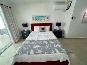Een hotelkamer met een bed, twee nachtkastjes, een schilderij en een airconditioning.