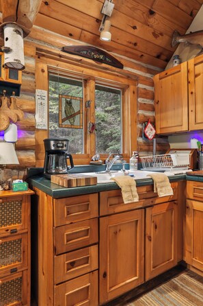 A cabin-style kitchen with wooden cabinets, a coffee maker, and a window with an owl decoration. - 3-bedroom log cabin in tranquil Sturgeon Bay close to Lake Michigan (Sturgeon Bay)