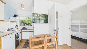 Una cocina funcional con estufa, lavamanos y comedor con mesa y silla de madera.