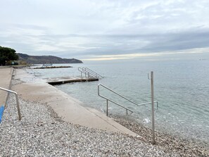Eine kieselsandige Uferpromenade mit Betonweg und Metallgeländern.