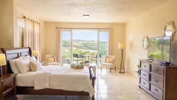 Una habitación de hotel con cama, televisión, cómoda y balcón con vistas.