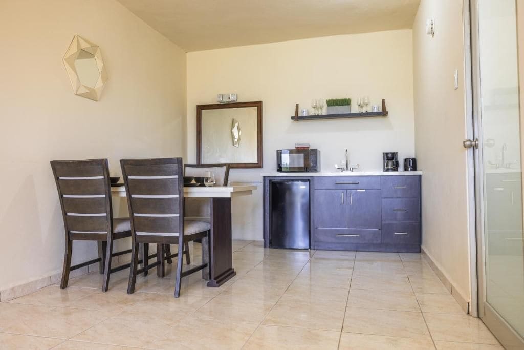 Una cocina compacta con comedor, que incluye microondas, cafetera y un refrigerador pequeño.