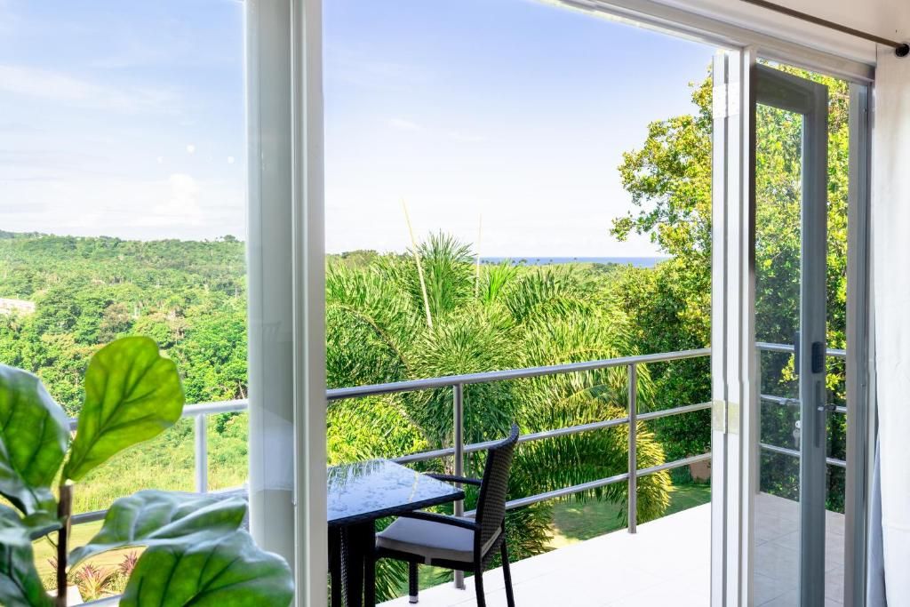 Un balcón con una mesa y una silla, con vistas a un paisaje verde exuberante y una masa de agua.