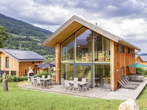 A modern wooden cabin with a large glass facade, outdoor seating, and a deck. - One-bedroom Cabin (Sankt Georgen am Kreischberg)