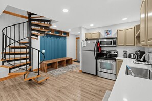 Cozinha moderna com forno embutido, micro-ondas e geladeira de aço inoxidável.