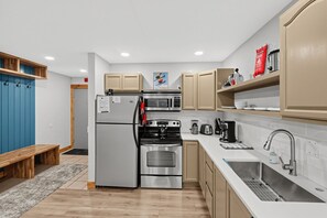 Eine moderne Küche mit Kühlschrank, Herd, Mikrowelle, Backofen, Spüle und verschiedenen Geräten.