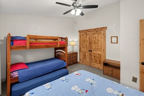 Ein Zimmer mit Etagenbetten, einem Schreibtisch, einem Kleiderschrank und einem Deckenventilator.