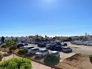 A parking lot with multiple cars and RVs, surrounded by buildings and palm trees. - Apartment in Nerja Near Balcon de Europa (Nerja)