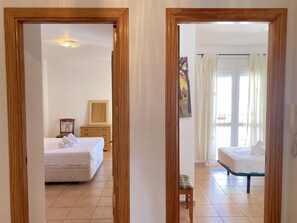 A hotel room with a bed, a wooden dresser, a chair, and a window with curtains. - Apartment in Nerja Near Balcon de Europa (Nerja)