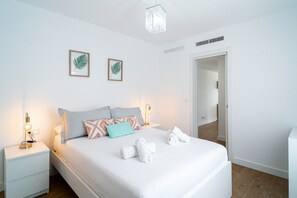 Ein Hotelzimmer mit einem Bett, Nachttischen, einer Lampe, einer Chandelier und einer Tür.