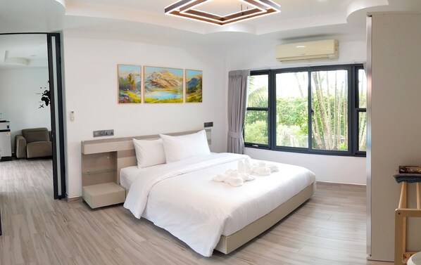 A modern hotel room with a large bed, a window with a view of trees, and a painting on the wall.