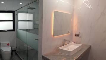 Une salle de bain moderne avec une douche à parois de verre, un lavabo en marbre et un miroir fixé au mur.