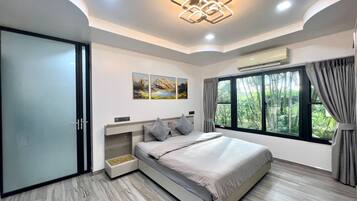 Une chambre moderne avec un lit, une fenêtre avec des rideaux, un climatiseur fixé au mur et un luminaire au plafond.