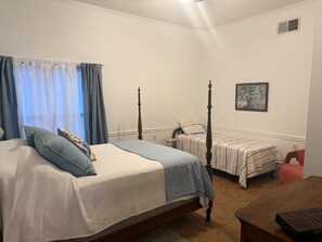 Un dormitorio con una cama grande, dos camas más pequeñas, un escritorio y una silla.