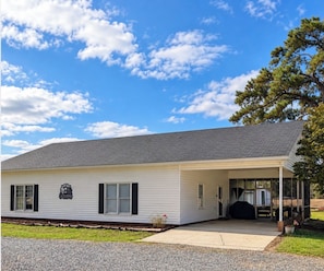 A single-story building with a covered porch, a small front yard, and a clear sky.