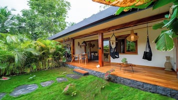 A modern house with a wooden deck, a covered outdoor seating area, and lush greenery.