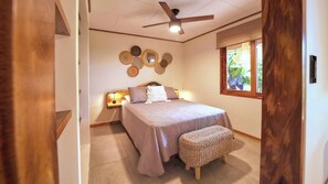 Quarto com cama, mesa de cabeceira, decoração na parede e janela com vista.