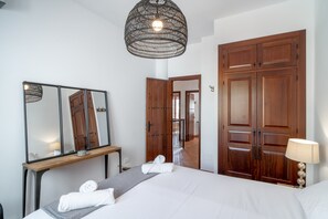 Ein Hotelzimmer mit Bett, Nachttisch, Spiegel, Kleiderschrank und einer Pendelleuchte.