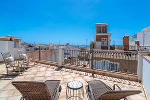 Eine Dachterrasse mit Gartenmöbeln, einem Pool und Blick aufs Meer.