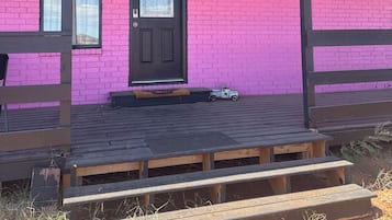 A building with a pink brick exterior, a black door with a star emblem, and a small toy car on the porch.