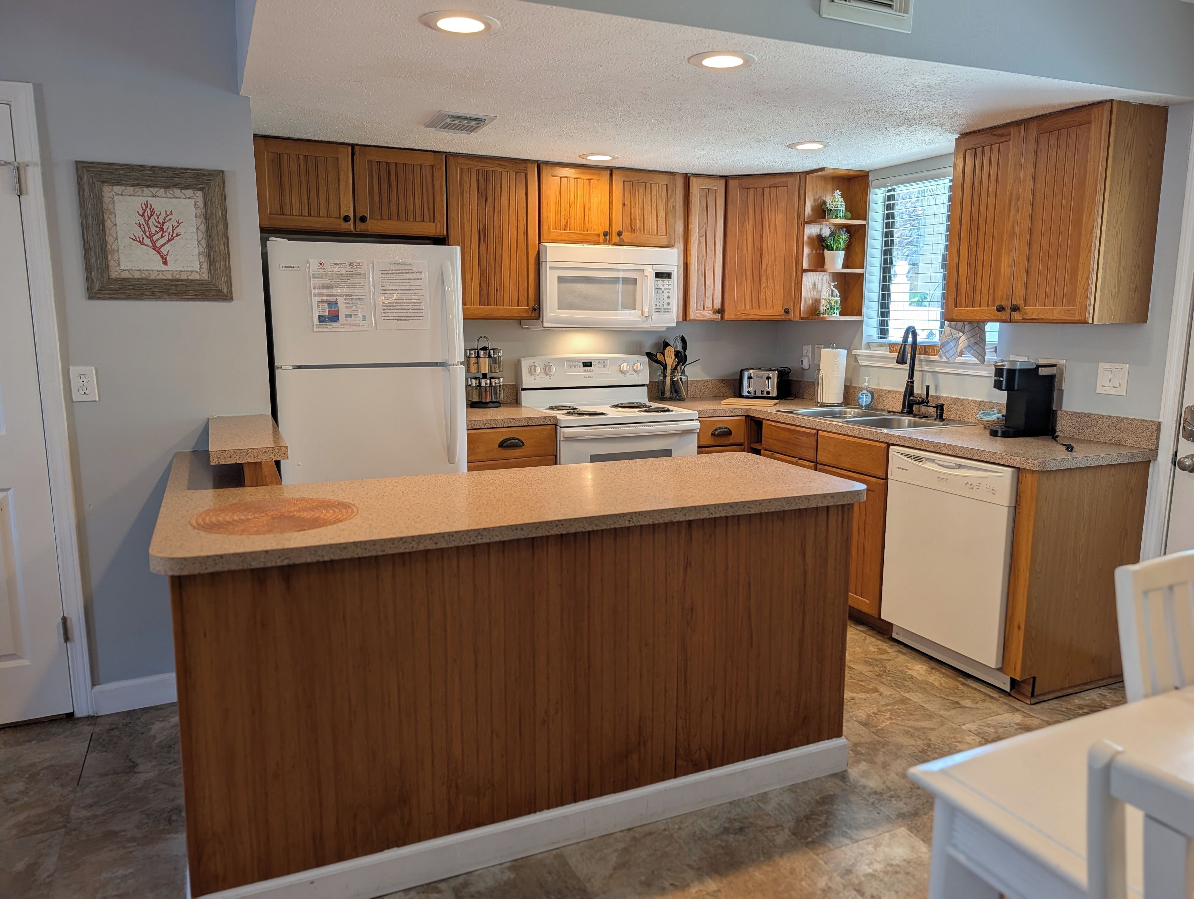 A kitchen with wooden cabinets, a central island, a refrigerator, a microwave, a stove, and a dishwasher.