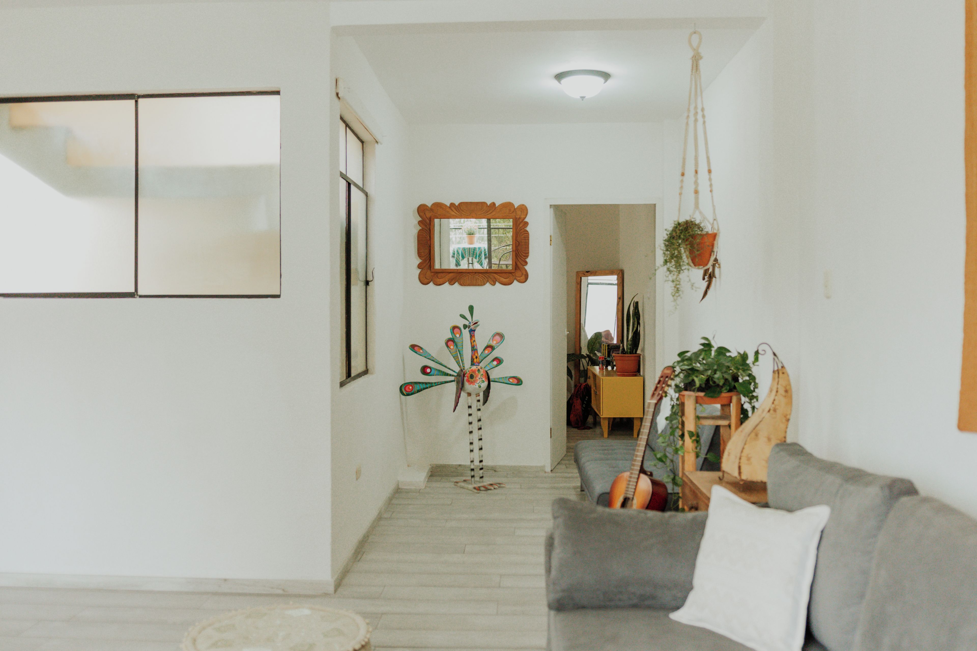 A living room with a grey sofa, a decorative peacock sculpture, and a hanging plant.
