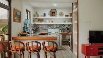 Una cocina compacta con una isla central, estufa y televisor.