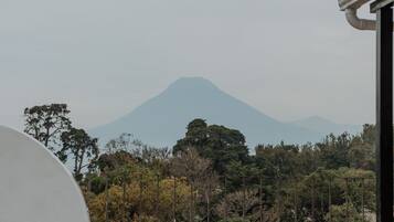 A view of a mountain from a balcony with a white wall and tiled floor.
