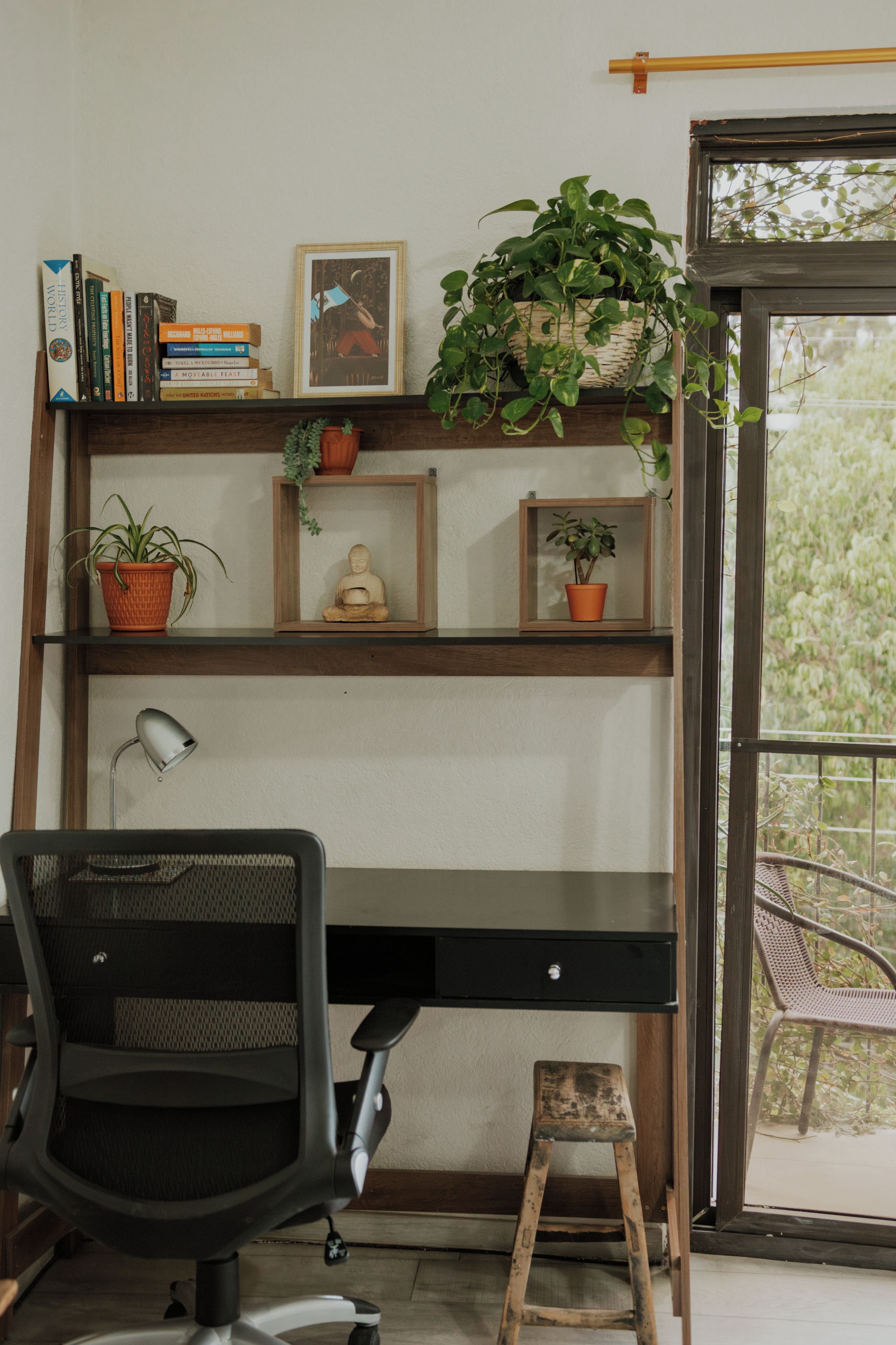 Un espacio de trabajo en casa con escritorio, silla y estanterías con libros y plantas.