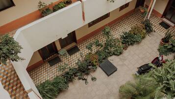 A multi-level atrium with a checkered floor pattern, multiple potted plants, and a parked scooter.