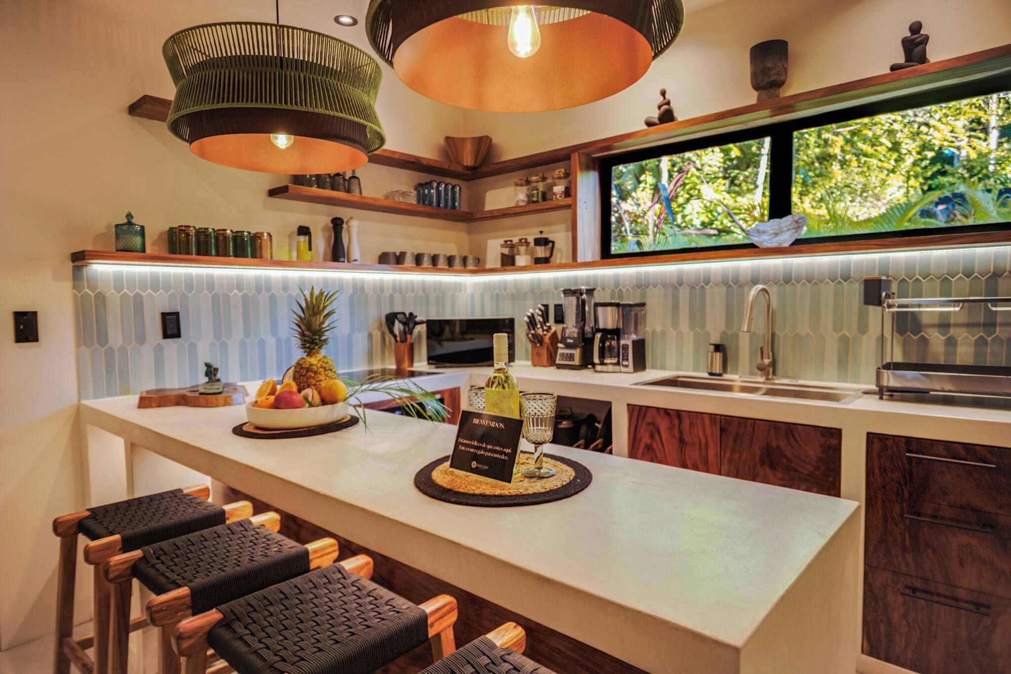 Una cocina moderna con una isla central, taburetes de bar y vistas al exterior.