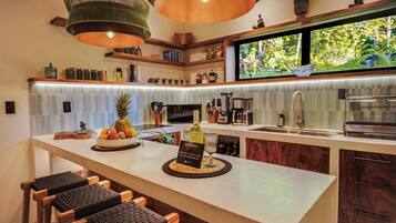 Una cocina moderna con una isla central, taburetes de bar y vistas al exterior.
