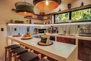 Una cocina moderna con una isla central, taburetes de bar y vistas al exterior.